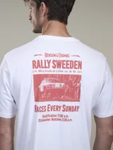 Remera blanca de algodón con estampado gráfico en la espalda en color rojo. El estampado incluye el texto "Benson & Thomas Rally Sweeden", una imagen de un auto de rally clásico y detalles de horarios de carreras.