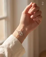 Pulsera de plata 925 con dije de mano de Hamsa decorado con circonias brillantes y un símbolo de infinito en el centro.