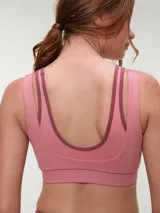 Top deportivo rosa con efecto layering, escote redondo bajo y tirantes dobles. Presenta el logo de la marca en tono oscuro en el frente.