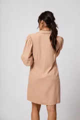 Vestido corto color tostado, con cuello solapa, abotonado al frente y mangas 3/4 con puños fruncidos.