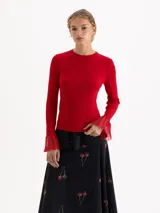 Top de tejido de punto acanalado color rojo, con cuello redondo, ajuste al cuerpo y mangas largas que finalizan en un detalle de volados acampanados con tejido calado.