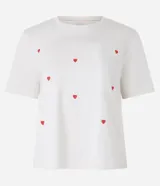 Remera de manga corta color crema con bordado de corazones rojos.