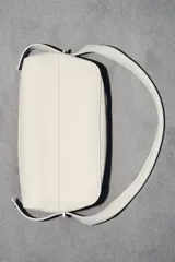 Bolso alargado de piel color blanco hueso, con asa de hombro y cierre de cremallera.