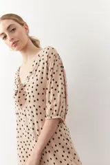 Vestido corto con estampado animal print en tonos beige y negro. Tiene mangas tres cuartos con elástico, cut-out en el frente y lazo.