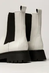 Bota Chelsea color verde militar de cuero, con elásticos laterales negros, tirador trasero y suela track negra.