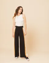 Pantalón palazzo color beige con cintura elastizada y dos franjas verticales en los laterales, una plateada y otra blanca.