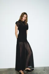 Vestido midi negro de cuello alto y sin mangas, con detalle drapeado en la parte superior y falda plisada. Incluye forro interior con tirantes finos ajustables y cierre lateral con cremallera oculta.