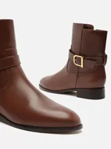 Bota corta negra de cuero con hebilla metálica plateada.