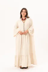 Vestido largo beige de silueta oversize, confeccionado en tela ligera con textura y motivos bordados tono sobre tono. Presenta escote en V, mangas amplias con volados y un gran volado en el ruedo.