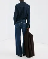 Jeans de denim azul de corte wide leg, tiro medio y diseño clásico de cinco bolsillos con cierre frontal de botón y cremallera.