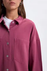 Sobrecamisa de denim color bordó, de corte oversize, con mangas largas, bolsillos frontales con solapa y cierre de botones metálicos.