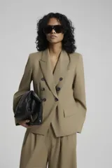 Saco negro de lana con calce entallado, cruzado con botones dorados con pie en delantero y bolsillos sastreros en delantero con tapa.