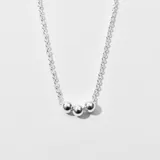 Collar plateado con cadena de eslabones y tres dijes esféricos.