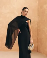 Vestido largo negro con escote bardot, detalle de nudo en la parte delantera y abertura lateral.