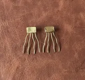 Aros de bronce con diseño geométrico y flecos metálicos ondulados colgantes.