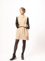 Vestido corto negro con mangas 3/4 verdes, cuello bote y bolsillos laterales.