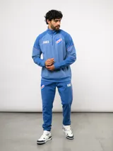 Buzo deportivo de medio cierre marca Umbro del Club Nacional de Football. Presenta un diseño en tonos azul y gris jaspeado, con cuello alto, mangas largas y detalles de costuras en contraste. Incluye el escudo del club y logo de la marca en el pecho.