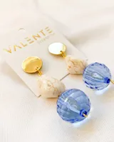Aros colgantes con base dorada, piedra blanca con vetas marrones y esfera facetada azul.