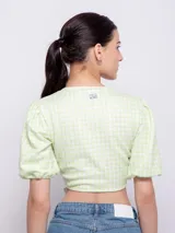 Top estampado con flores rosas, hojas verdes y líneas negras, de manga corta abullonada con nudo en el escote.