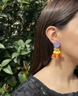Aros colgantes con base redonda lila y diseño de cascada con piezas geométricas en tonos naranja y amarillo.