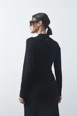 Polera de tejido de punto color beige, con cuello alto, manga larga y detalle de lazo ajustable en la cintura que aporta estructura a la silueta.