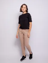 Pantalón tipo babucha de corte deportivo, color beige, con cintura elástica ajustable mediante cordón, puños en los tobillos y bolsillos frontales.