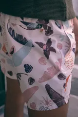 Short de baño blanco con estampado de hojas de palmera, piñas y sandías en tonos pastel.