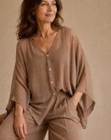 Camisa oversize color marrón claro, confeccionada en tejido translúcido, con cuello en V, mangas amplias estilo murciélago y cierre frontal con botones.