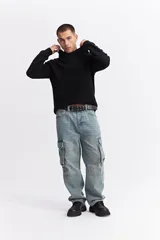 Canguro de punto negro con capucha, de corte relajado y textura acanalada. Presenta puños y ruedo tejidos.