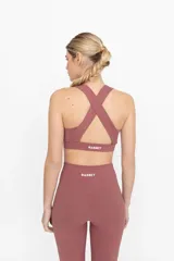 Top deportivo color ladrillo con espalda cruzada y compresión alta.