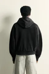 Sudadera con capucha de corte relajado, confeccionada en tejido de algodón con efecto lavado. Presenta manga larga, bolsillo frontal tipo canguro y terminaciones en rib.