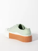 Zapatilla acordonada de textil color verde menta, con plataforma de goma bicolor en blanco y naranja con textura en relieve.
