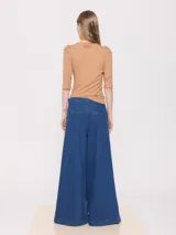 Pantalón de jean azul de corte wide leg y tiro medio-alto, con pinzas en la cintura y terminación de sastrería.