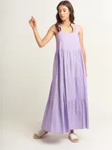 Vestido largo lila con volados en diferentes tamaños, escote cuadrado y lazos en la espalda.