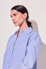 Camisa celeste con rayas verticales blancas, de corte clásico, con cuello camisero y mangas largas.