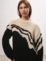 Buzo de lana merino con diseño de ondas en contraste de colores blanco y negro, cuello redondo y mangas largas.