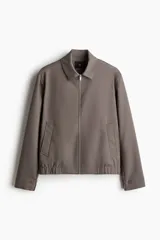 Campera de sarga color marrón topo, con cuello camisero, cierre frontal y bolsillos insertados al bies. Posee elástico revestido en puños y bajo.