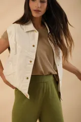 Chaleco color crudo con cuello camisero, abotonado al frente y bolsillos de parche.