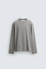 Camiseta de manga larga con corte relajado, confeccionada en tejido de algodón gris melange, con cuello redondo acabado en rib.