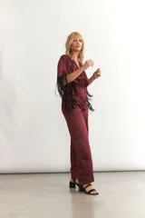 Mono largo color borgoña de seda sintética, con escote en V cruzado, mangas cortas amplias con flecos y cintura elastizada.