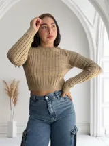 Sweater tejido de punto color beige, con cuello redondo y mangas largas.