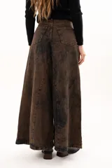 Pantalón de jean de tiro alto con corte wide leg y diseño de paneles verticales. Presenta un acabado lavado con efecto desgastado en tono chocolate, bolsillos funcionales y cierre frontal con botón metálico.