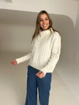 Jersey de punto color crudo con cuello alto y diseño acanalado vertical. Presenta un corte holgado y mangas largas con puños ajustados.