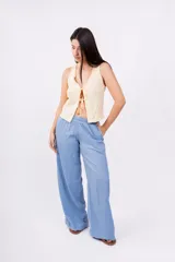 Chaleco corto sin mangas color verde salvia, confeccionado en tela perforada (broderie o calado). Presenta escote en V con lazos ajustables en el centro frontal.