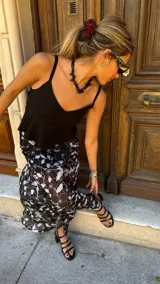 Falda larga de tela estampada con flores y hojas en tonos marrones, negros y violetas. Tiene elástico en la cintura.