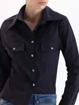 Camisa entallada de poplín color negro, con cuello clásico, cierre frontal de botones, mangas largas con puños anchos y bolsillos frontales con tapa.