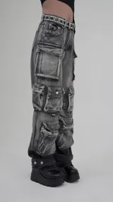 Pantalón jean gris oscuro con efecto desgastado, tiro alto, corte amplio y múltiples bolsillos tipo cargo.