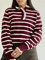 Sweater de punto a rayas horizontales en color bordó y blanco, con cuello tipo polo, cierre frontal con botones y delicados detalles de puntilla blanca en el cuello y los puños.