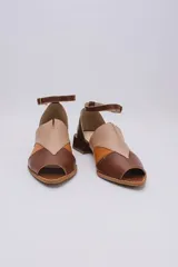Sandalias de cuero color marrón, con combinaciones de color beige y naranja. Tiene tira ajustable con hebilla en el tobillo y taco bajo.