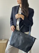 Cartera tipo tote de cuero graneado negro, con diseño clásico y textura uniforme. Cuenta con doble asa de hombro, bolsillo frontal con cierre magnético, bolsillo trasero con cierre metálico y compartimento principal con cierre. El interior está forrado y dispone de múltiples bolsillos organizadores.
